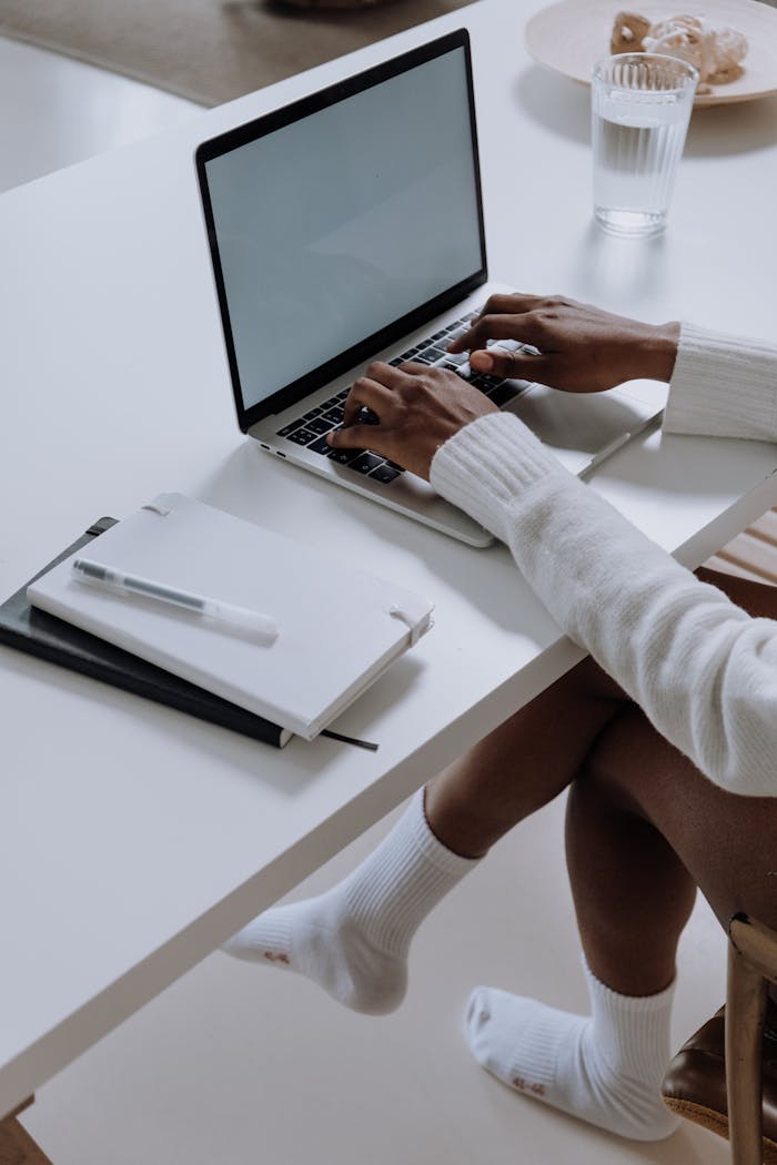 Person in White Long Sleeve Shirt Using Macbook Pro